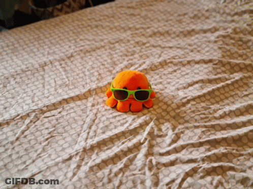 Stuffed Octopus Wearing Green Sunglasses On Bed GIF