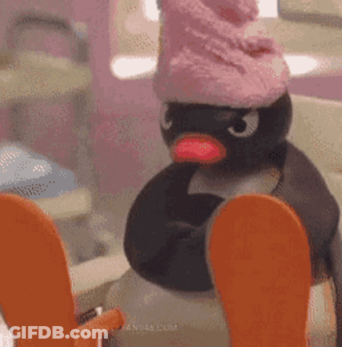 Stuffed Penguin In Pink Hat Sitting On Toilet GIF