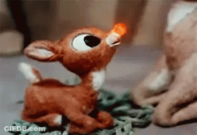 Stuffed Reindeer With Red Nose Sitting On Table GIF