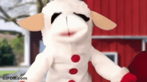 Stuffed Sheep Standing In Front Of Red Barn GIF