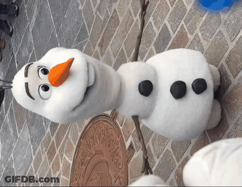 Stuffed Snowman With Orange Nose On Brick Wall GIF