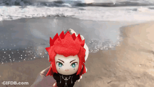 Stuffed Toy With Red Hair And Green Eyes On Beach GIF