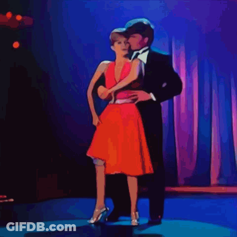 Suit-And-Tie Man Dancing With Woman In Red Dress GIF