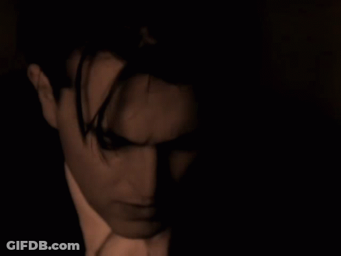 Suit-And-Tie Man Looking At Camera In Dark Room GIF