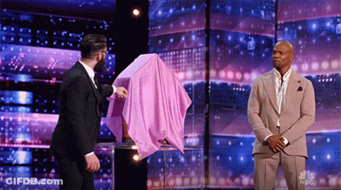 Suited Man Holds Pink Cloth Over Another's Head GIF