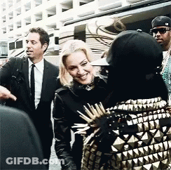 Suited Man Talking To Woman In Spiked Jacket GIF
