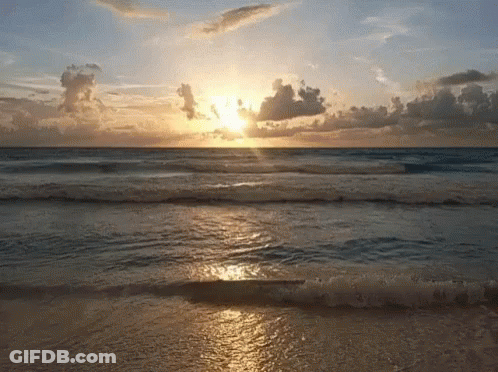 Sun Setting Over Ocean Waves On Beach GIF