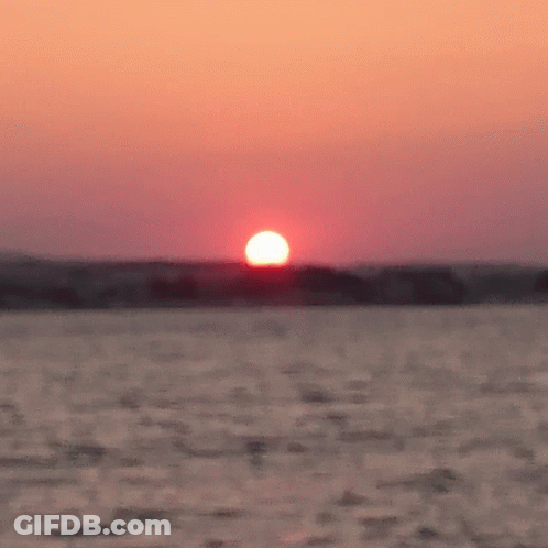 Sun Setting Over Ocean With Boat GIF