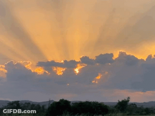 Sun Shining Through Clouds At Sunset Over Field GIF