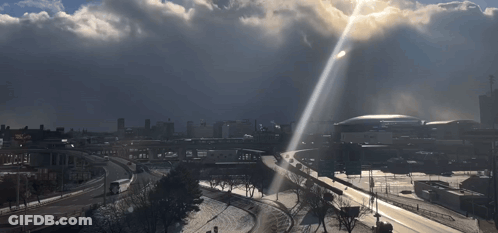 Sun Shining Through Clouds Over City GIF