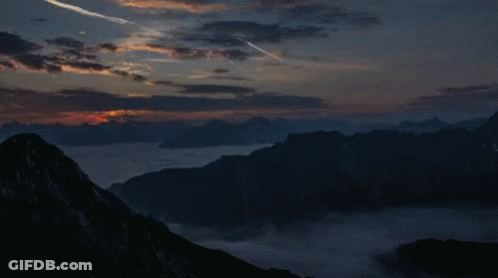 Sunset Over Mountain Range With Plane Flying GIF