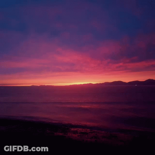 Sunset Over The Ocean With Mountains In The Background GIF