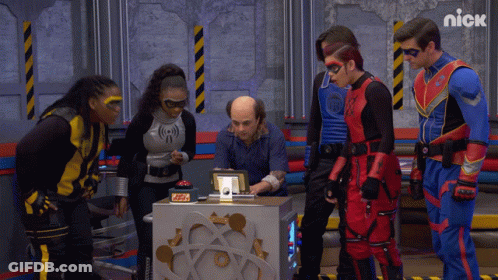 Superhero Group Standing Around Box Saying Nick GIF