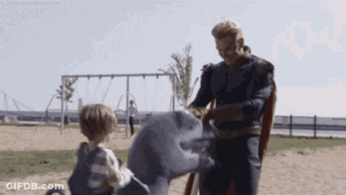 Superhero Man Playing With Child On Shark Statue GIF