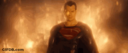 Superman Is Standing In Front Of A Fire And Looking At The Camera . GIF