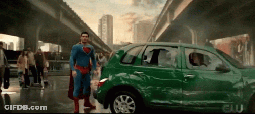 Superman Is Standing In Front Of A Green Car That Has Been Damaged GIF