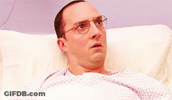 Surprised Man With Glasses Lying In Hospital Bed GIF
