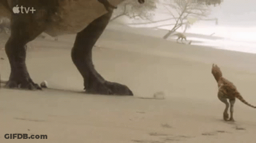 T-Rex Standing Next To Small Animal In Sand GIF