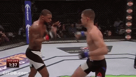 Tattooed Man Standing Before Tapout Punching Bag GIF