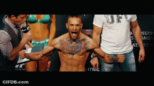 Tattooed Man Standing In Front Of Bikini Woman And UFC Shirt Man GIF