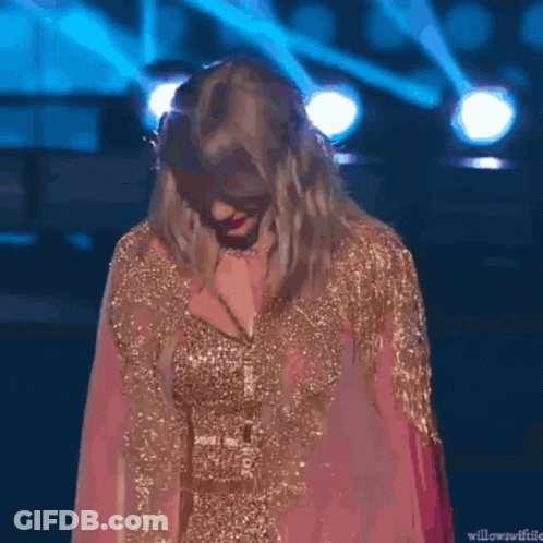 Taylor Swift In Pink And Gold Dress Smiling On Stage GIF