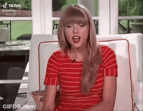Taylor Swift In Red Striped Shirt Sitting With Mouth Open GIF