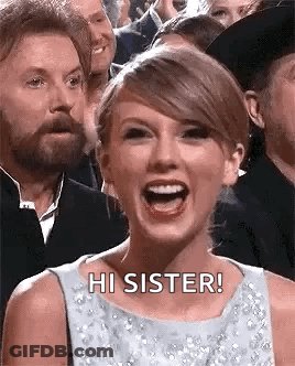 Taylor Swift Is Laughing In Front Of A Crowd Of People While A Man Looks On . GIF