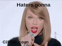 Taylor Swift Is Singing Into A Microphone With The Words `` Haters Gonna '' Written Above Her . GIF