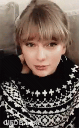 Taylor Swift Sitting On Couch In Black And White Sweater GIF