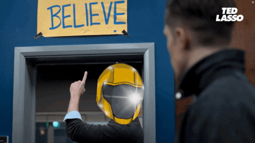 Ted Lasso Wearing Helmet Points Believe Sign GIF