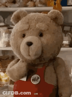 Teddy Bear In Red Apron With Help Button Next To Refrigerator GIF