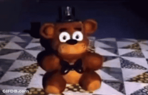Teddy Bear Sitting On Quilt On Bed GIF