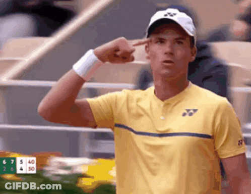 Tennis Player In Yellow Shirt And White Hat Pointing At Head GIF