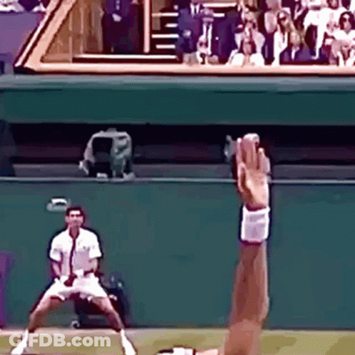 Tennis Player Reaching For Ball While Another Watches GIF