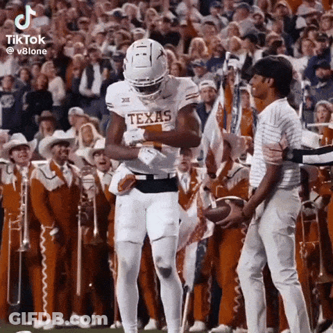 Texas Football Player Holding Ball In Front Of Crowd GIF