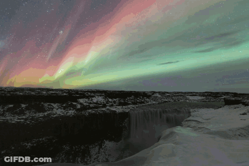 The Aurora Borealis Is Shining Over A Waterfall GIF