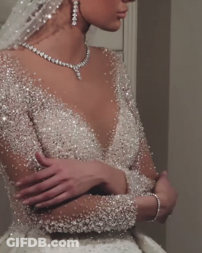 The Bride Is Wearing A Necklace And Earrings And A Veil GIF