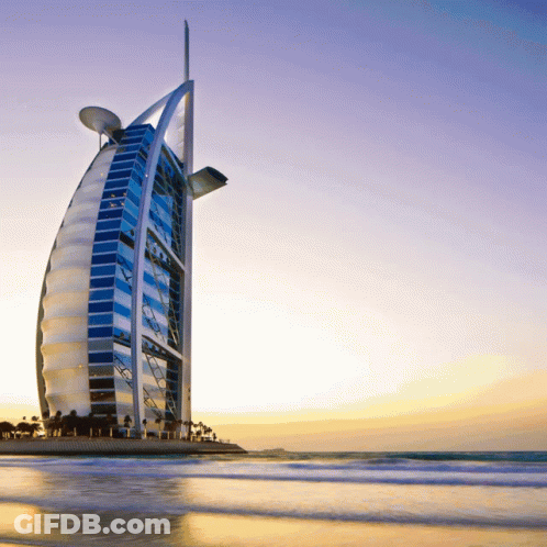 The Burj Khalifa Is A Very Tall Building Sitting On Top Of A Beach GIF