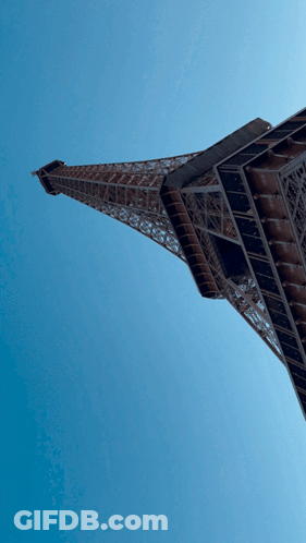 The Eiffel Tower Is Against A Blue Sky GIF