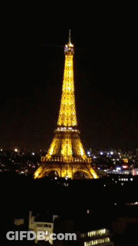 The Eiffel Tower Is Lit Up At Night With A Light Coming Out Of The Top GIF
