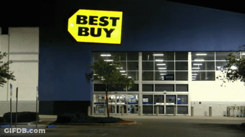 The Front Of A Best Buy Store At Night With A Parking Lot In Front Of It GIF