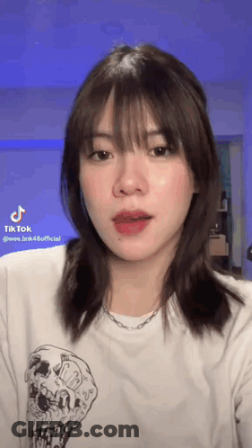 The Girl Is Wearing A White T-Shirt With A Skull On It And A Necklace . GIF