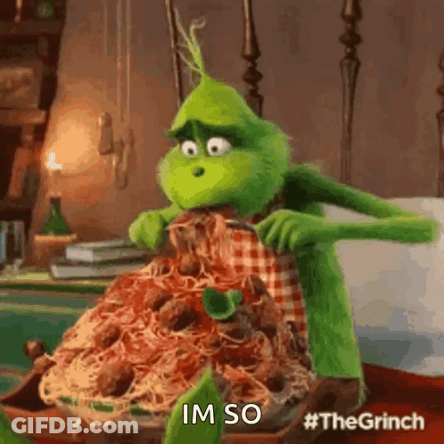 The Grinch From The Movie The Grinch Is Sitting On A Bed Eating A Pile Of Spaghetti And Meatballs . GIF