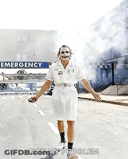 The Joker Is Dressed As A Nurse And Is Walking Down The Street . GIF