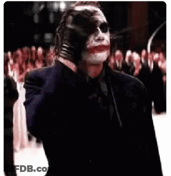 The Joker Is Holding A Gun In His Hand And Pointing It At The Camera . GIF