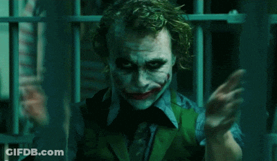 The Joker Is Holding A Knife In His Hand In A Dark Room . GIF