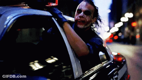 The Joker Is Sitting In The Back Of A Police Car And Looking Out The Window . GIF