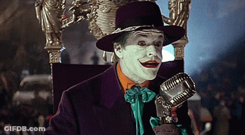 The Joker Is Sitting On A Throne Holding A Microphone In His Hand . GIF
