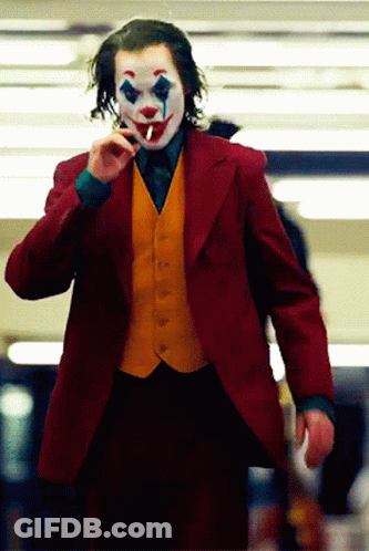 The Joker Is Smoking A Cigarette While Wearing A Red Jacket And Yellow Vest GIF