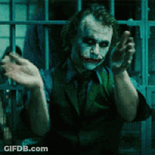 The Joker Is Standing In A Prison Cell With His Hands Up GIF